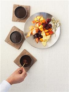 Hand dipping fruit in chocolate sauce