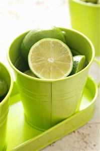 Whole and halved limes in a green beaker