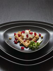 Heart-shaped wafer with goat cheese spread & pomegranate seeds