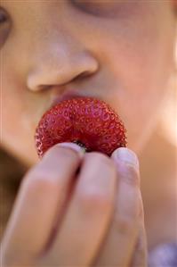 Girl biting into a strawberry