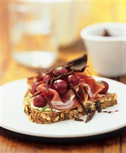 Raw ham, cherries and chocolate curls on wholegrain bread