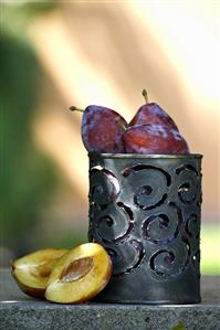 Plums in and beside metal container