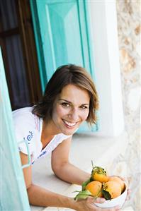 Woman holding a bowl of fresh oranges