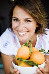 Woman holding a bowl of fresh oranges