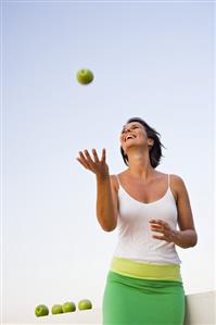 Woman playing with a green apple out of doors