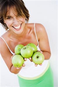 Young woman holding green apples in her hands