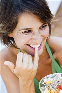 Young woman eating muesli with fresh fruit