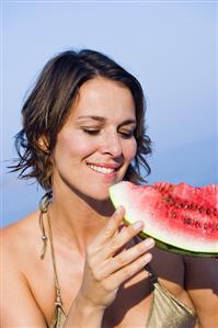 Young woman eating a slice of watermelon out of doors