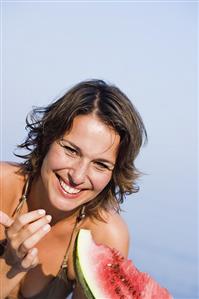 Young woman eating a slice of watermelon out of doors