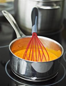 Cream of tomato soup in a pan with a whisk