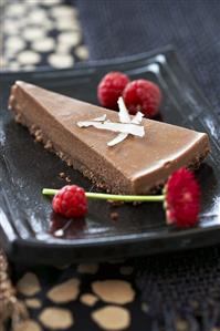 Piece of chocolate cake with coconut and raspberries