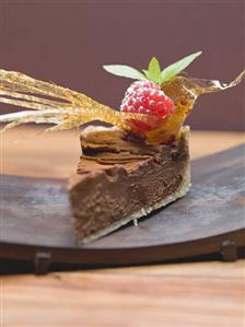 Piece of chocolate tart with caramel fan and raspberry