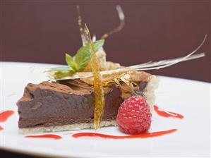 Piece of chocolate tart with caramel fan and raspberry