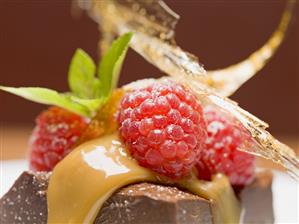 Piece of chocolate tart with raspberries & caramel (close-up)