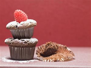 Chocolate muffins with icing sugar & raspberry, one eaten