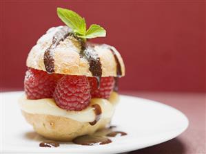 Profiterole with raspberries, vanilla cream, chocolate sauce, mint