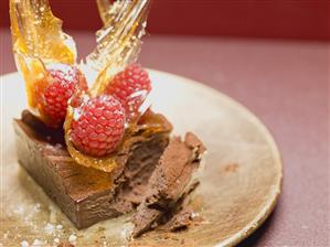 Small chocolate cake with raspberries & caramel fans, partly eaten