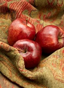 Three red apples on fabric