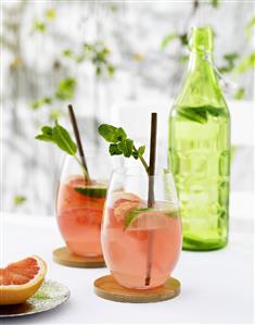 Pink grapefruit drinks with lime wedges and mint