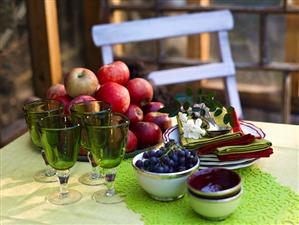 Plates, napkins, glasses and fruit on table in garden