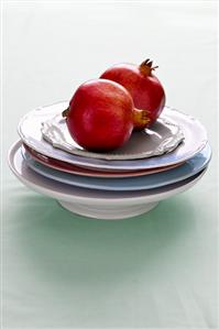 Two pomegranates on a stack of plates