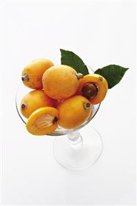 Several ripe medlars in a glass