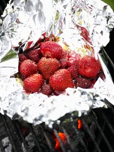 Strawberries and raspberries in aluminium foil on barbecue