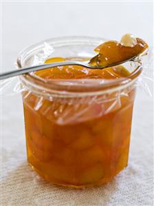 Apricot jam with almonds in jar and on spoon