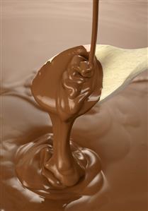 Melted chocolate for chocolate fondue running from wooden spoon