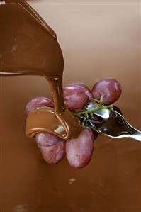 Pouring melted chocolate over grapes