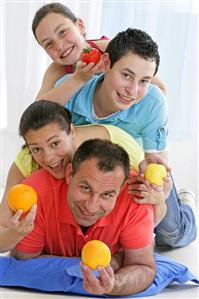 Cheerful family holding fruit and tomato