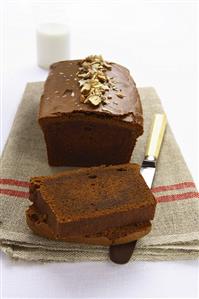 Chocolate loaf cake with chopped nuts, partly sliced