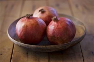 Three pomegranates in a wooden dish