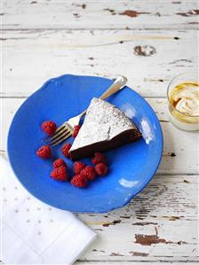 Chocolate tart dusted with icing sugar with fresh raspberries