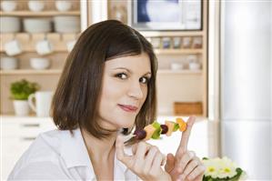 Young woman with fruit skewer