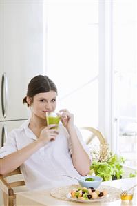 Young woman with fruit juice at breakfast table