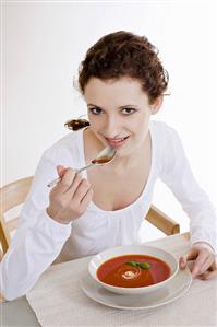 Young woman eating cream of tomato soup