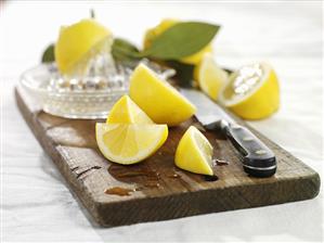 Pieces of lemon with squeezer on wooden board