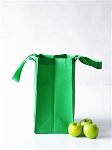 Three Granny Smith apples with a green shopping bag