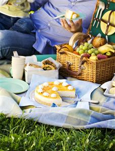 Picnic with fruit in picnic basket and mango cheesecake