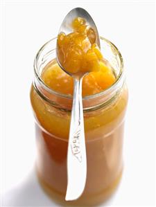 Peach and mango jam in jar with spoon