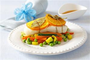 Baked halibut with orange slices on vegetables