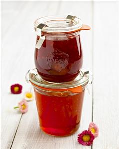 Two different jars of berry jam, one on top of the other