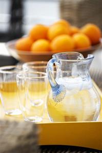 Jug of water and glasses on tray, oranges in background