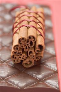 Cinnamon sticks, tied together with red ribbon, on chocolate