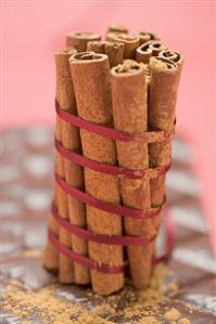 Cinnamon sticks, tied together with red ribbon, on chocolate