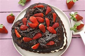 Heart-shaped chocolate cake with whipped cream & strawberries