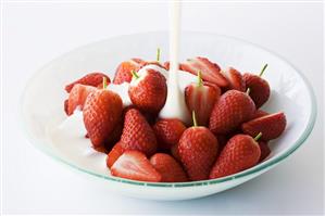 Pouring yoghurt over fresh strawberries