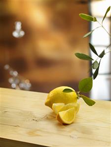 Lemon and lemon wedges with leaves on wooden table