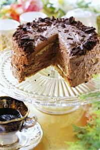 Rum chocolate cake, a piece removed, on cake stand